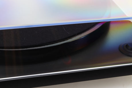 Close up of a used Rega RP1 Turntable in a cool grey finish showing a scratch on the left side of the lid