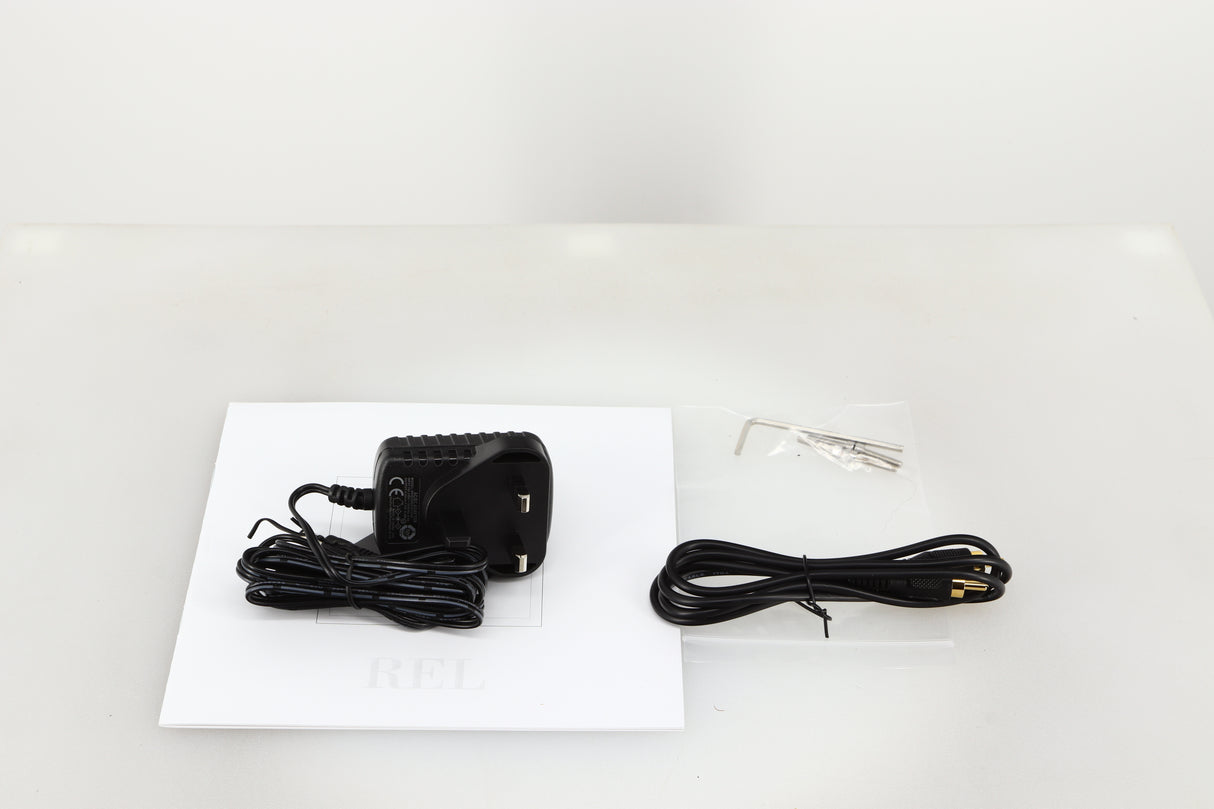 Accessories for a used REL Arrow V3 Wireless Subwoofer Transmitter showing Power Supply, Manual, Allen Key, Bolts and Interconnect Cable 