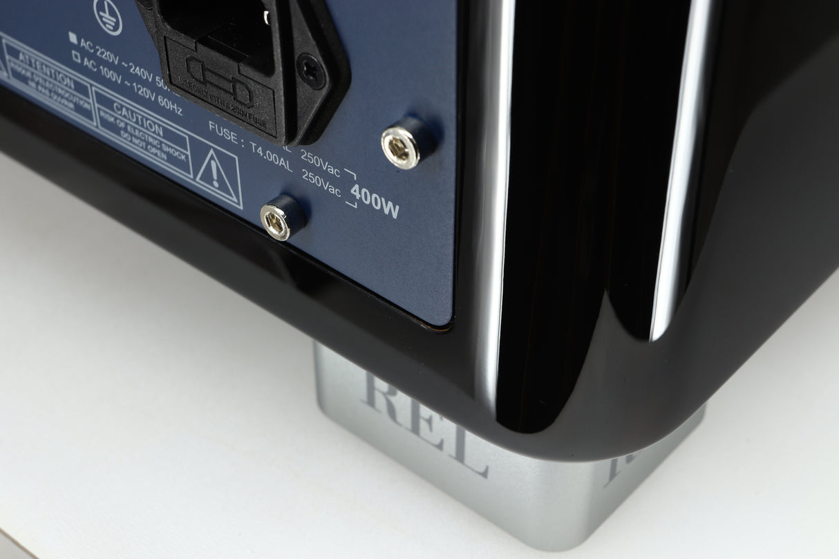 Close up of a used REL T-7X Subwoofer in a piano black finish showing very light scratch on rear