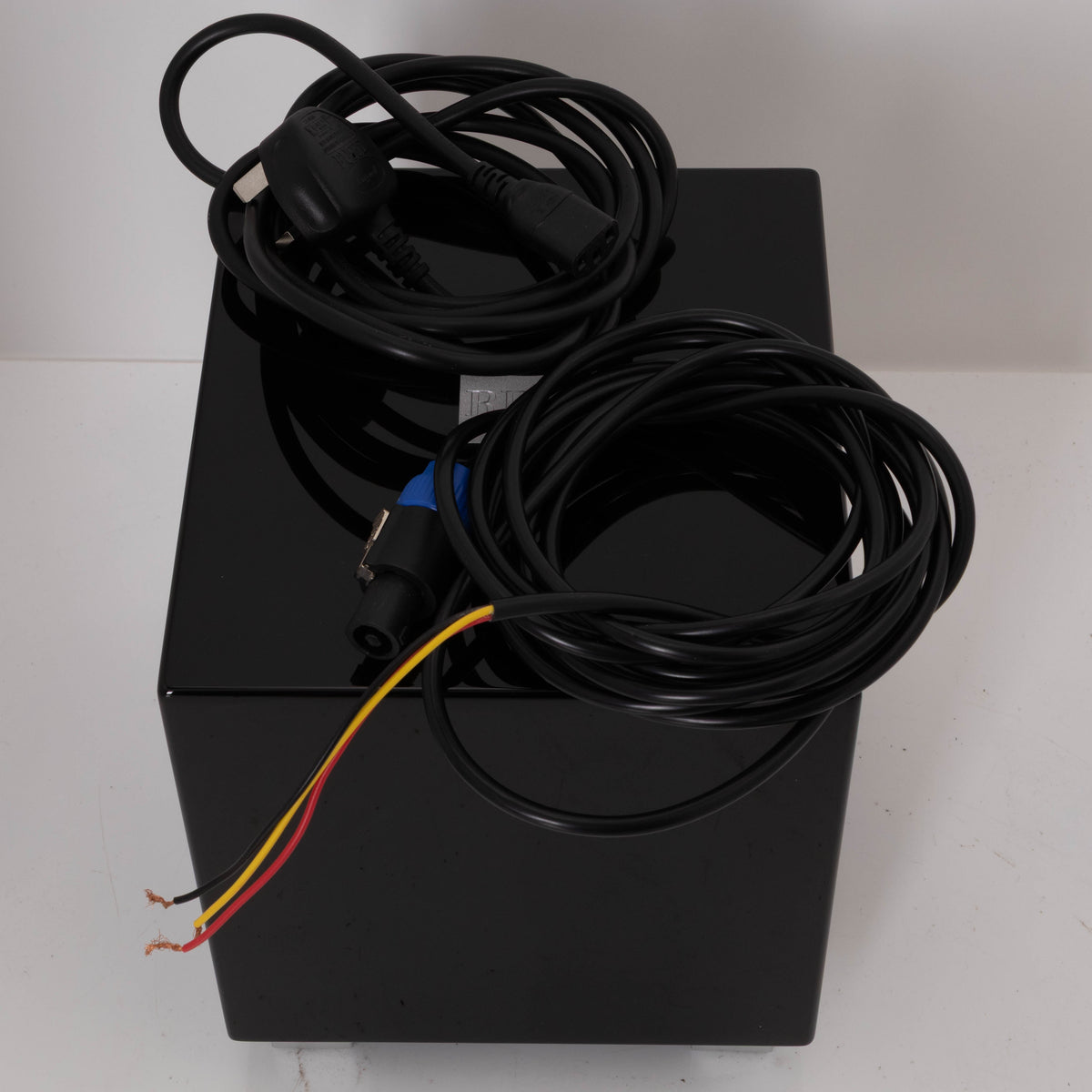 Top of a used REL T-Zero Subwoofer in a Piano Black finish showing Mains Cable and Hi-Level Cable