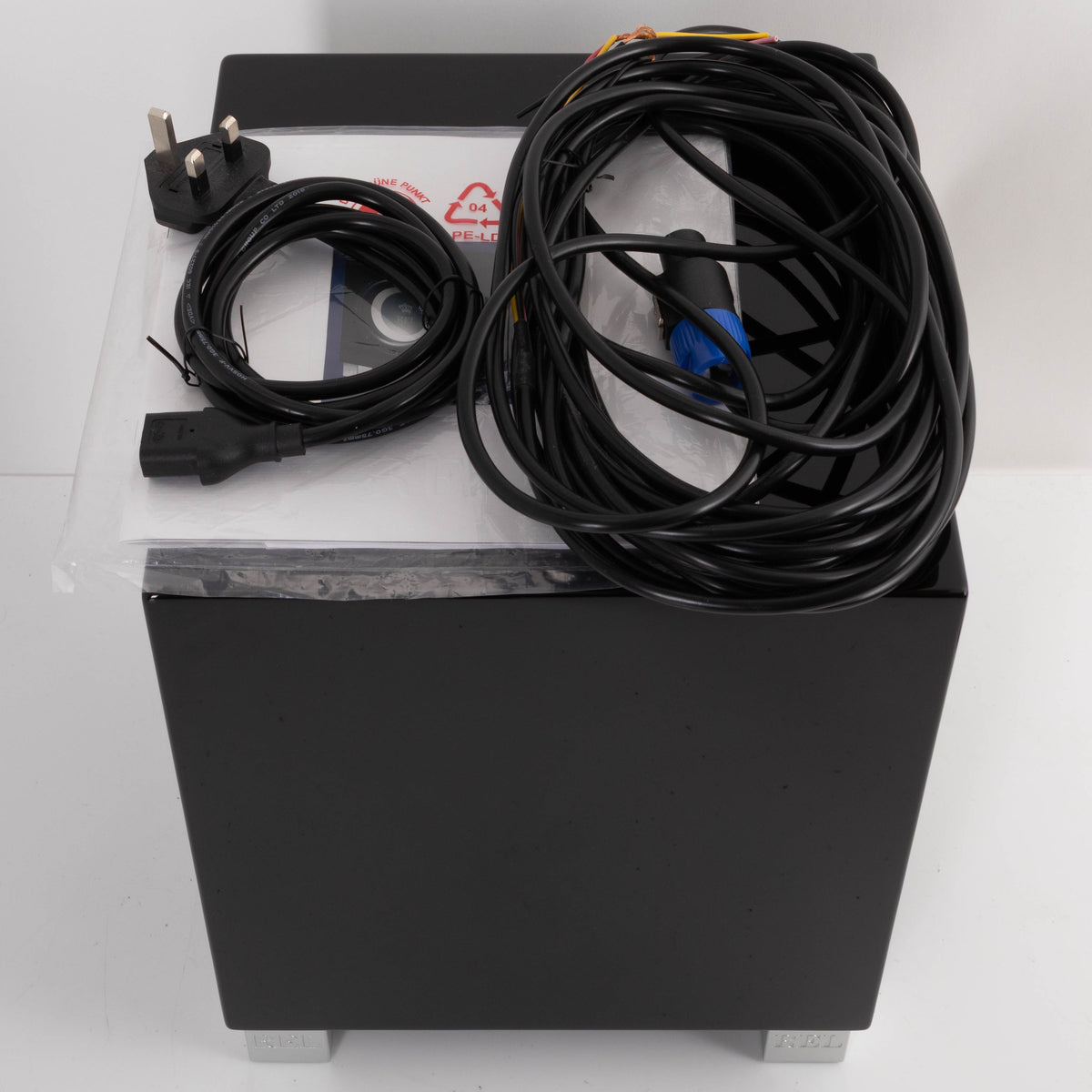 Top of a used REL T5i Subwoofer in a Piano Black finish showing Manual, Mains Cable and Hi-Level Cable