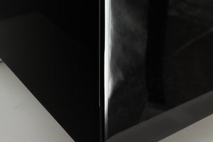 Close up of a REL T5i Subwoofer with a piano black finish showing feet like marks