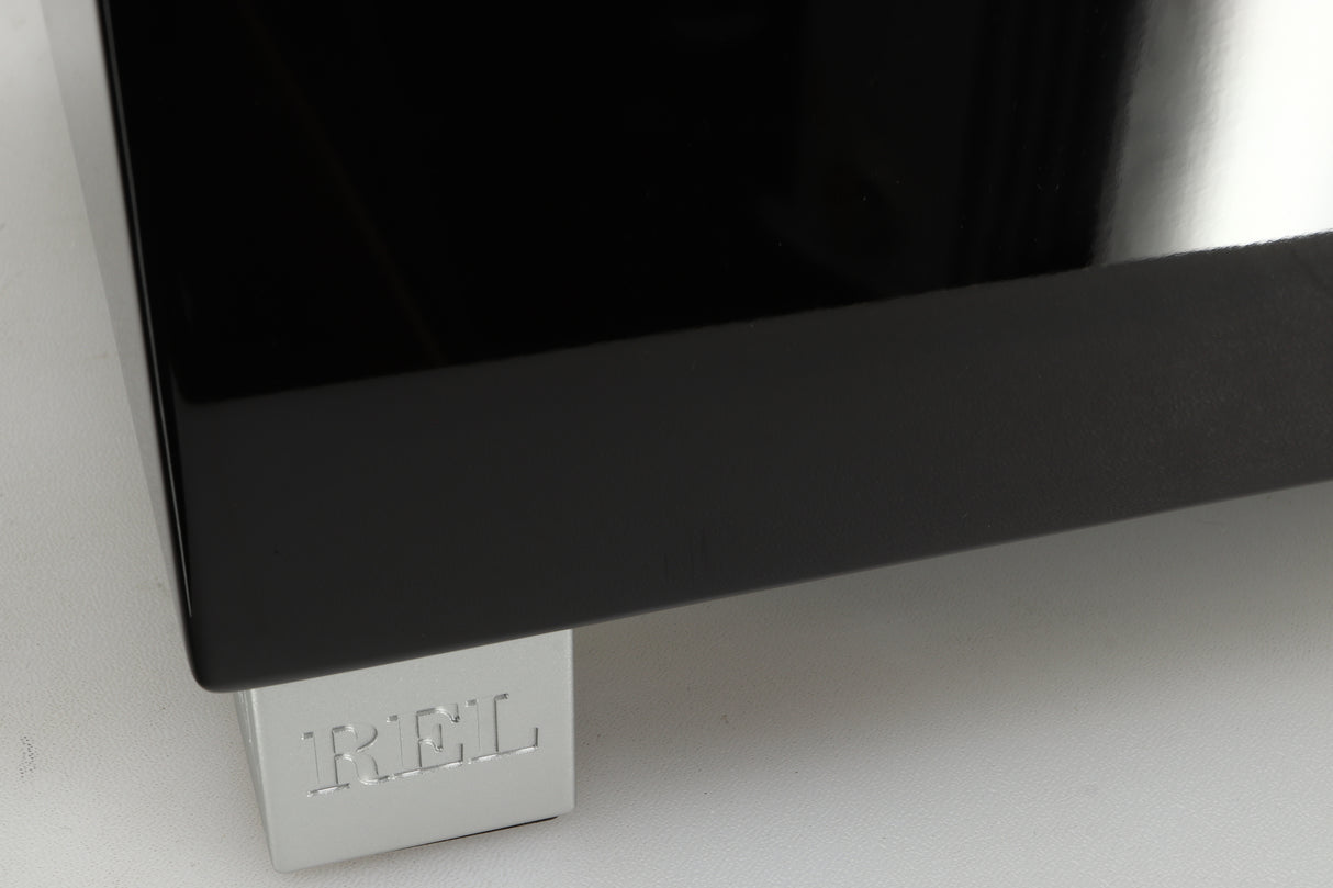 Close up of a REL T5i Subwoofer with a piano black finish showing a small scratch
