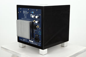 Rear left corner of a REL T5i Subwoofer with a piano black finish