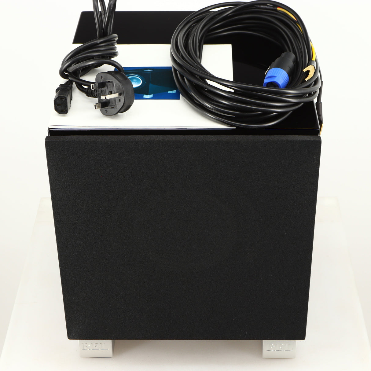 Top of a used REL T7i Subwoofer in a piano black finish showing Mains Cable, Hi-Level Cable and Manual