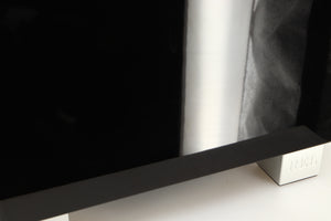 Close up of a used REL T7i Subwoofer in a piano black finish showing light scratches on left side