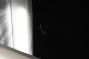 Close up view of a used REL T9X Subwoofer in Piano Black finish showing scratches on the left side 