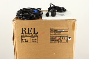 Box of a used REL T5X Subwoofer in Piano Black finish with mains cable, manual, and Hi level cable