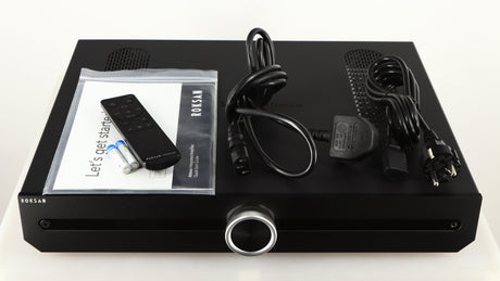 Top of a used Roksan Attessa Integrated Amplifier in a black finish showing Manual, Remote, 2x Batteries, Mains Cable and Schuko Cable
