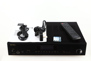 Top of a used Rotel A14 MKII Integrated Amplifier in a black finish showing Mains Cable, Batteries, Remote, Schuko Cable and Manual
