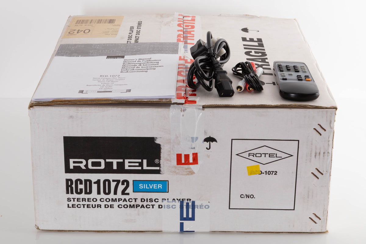 Box of a used Rotel RCD-1072 CD Player in Silver with mains cable, manual, remote, and interconnects
