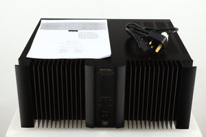 Top view of a used Rotel RMB1075 Power Amplifier in a black finish showing a manual and a mains cable 