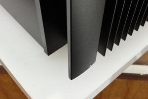 Close up of a used Rotel RMB1075 Power Amplifier in a black finish showing a small scratch on fascia