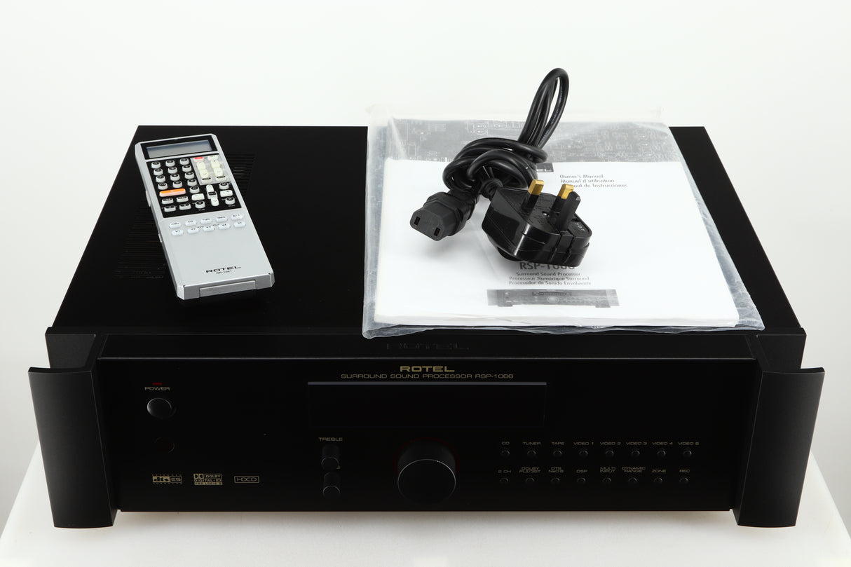 Top of a used Rotel RSP-1066 Pre Amplifier / Processor in a black finish showing Remote, Mains Cable and Manual 