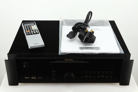 Top of a used Rotel RSP-1066 Pre Amplifier / Processor in a black finish showing Remote, Mains Cable and Manual 