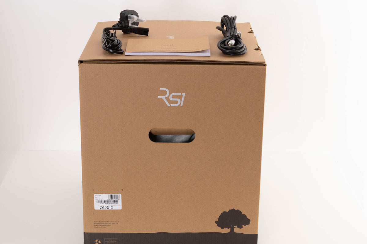 Box of a used Ruark Audio RS-1 Subwoofer in Soft Grey with mains cable, manual, and sub cable