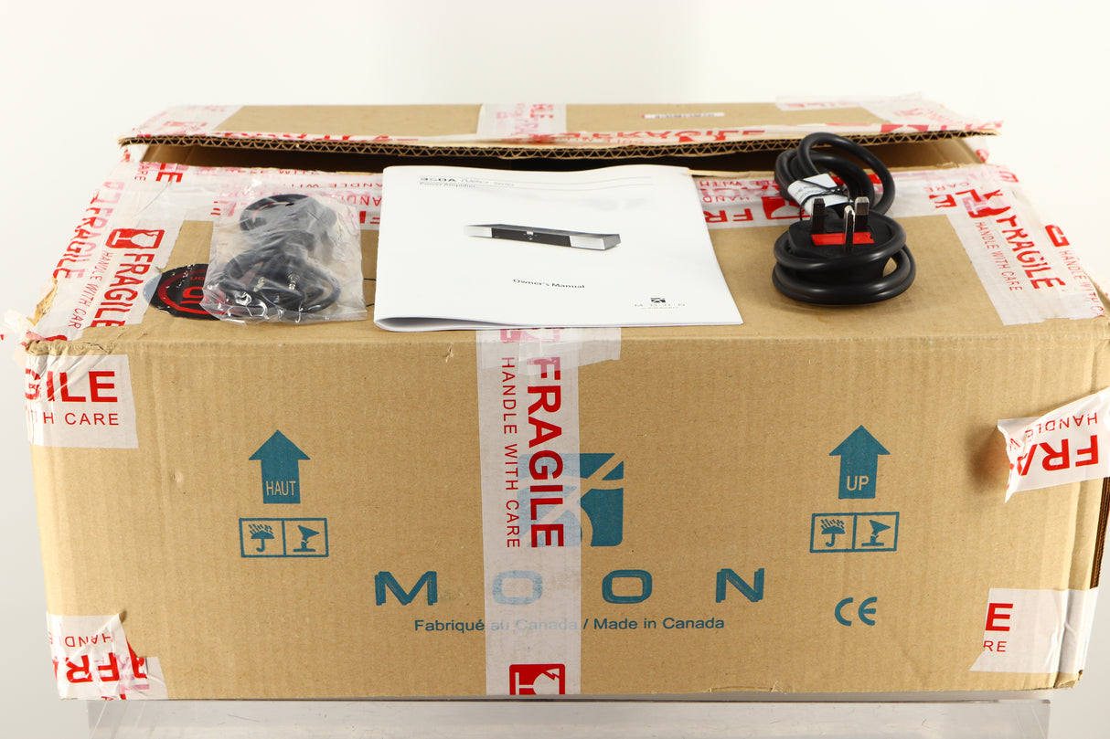 Box of a used Sim Audio Moon 330A Power Amplifier in Black finish with mains cable, manual, and 3.5mm cable 