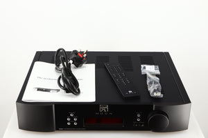 Top of a used Simaudio Moon 340i D3PX Integrated Amplifier in a black finish showing Manual, Battery, Remote, Mains Cable, Fuse and AUX Cable