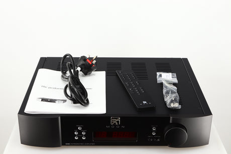 Top of a used Simaudio Moon 340i D3PX Integrated Amplifier in a black finish showing Manual, Battery, Remote, Mains Cable, Fuse and AUX Cable