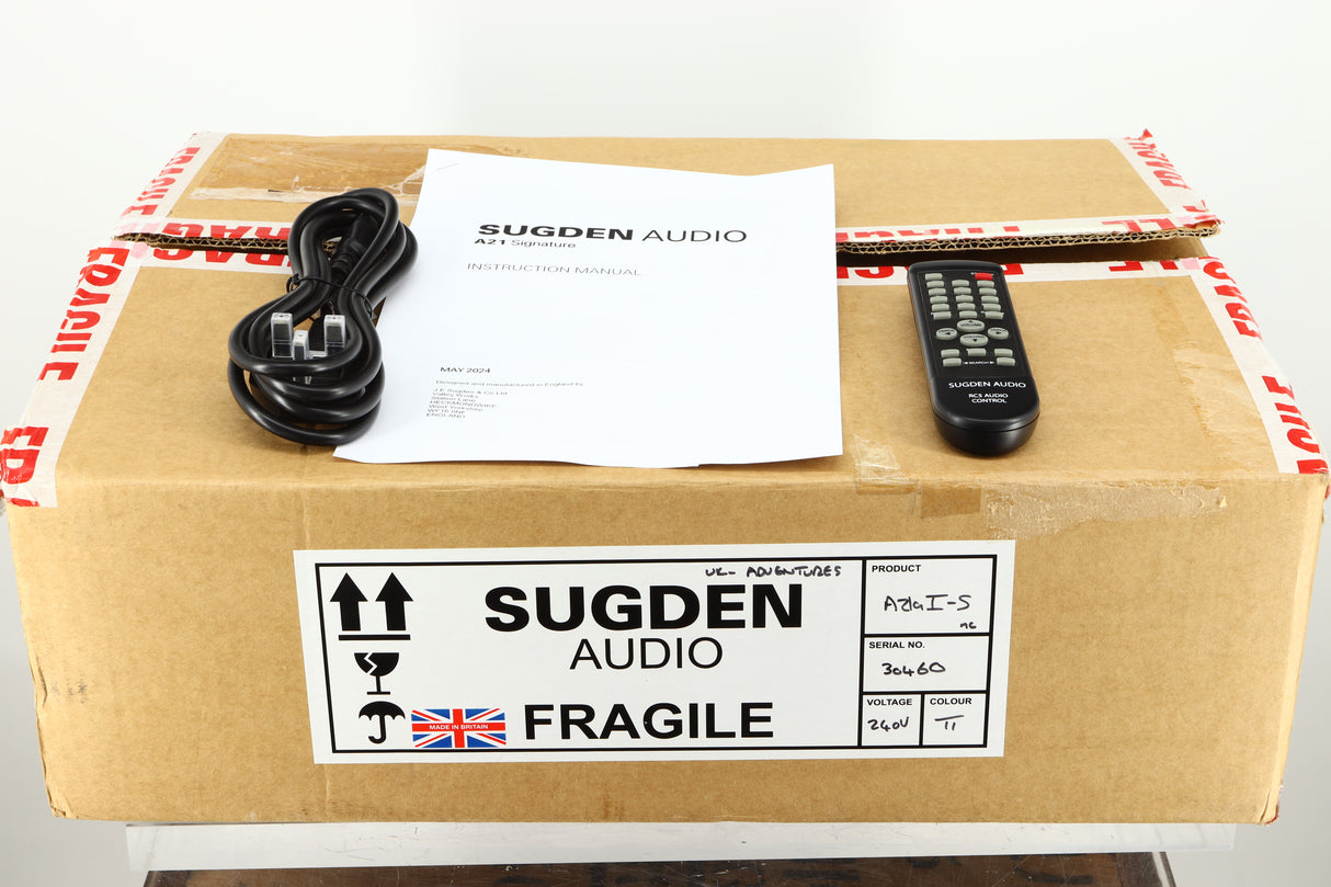 Box of a used Sugden A21 I-S Integrated Amplifier in Titanium finish showing mains cable and remote 