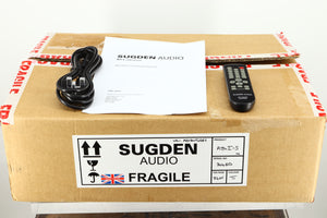 Box of a used Sugden A21 I-S Integrated Amplifier in Titanium finish showing mains cable and remote 