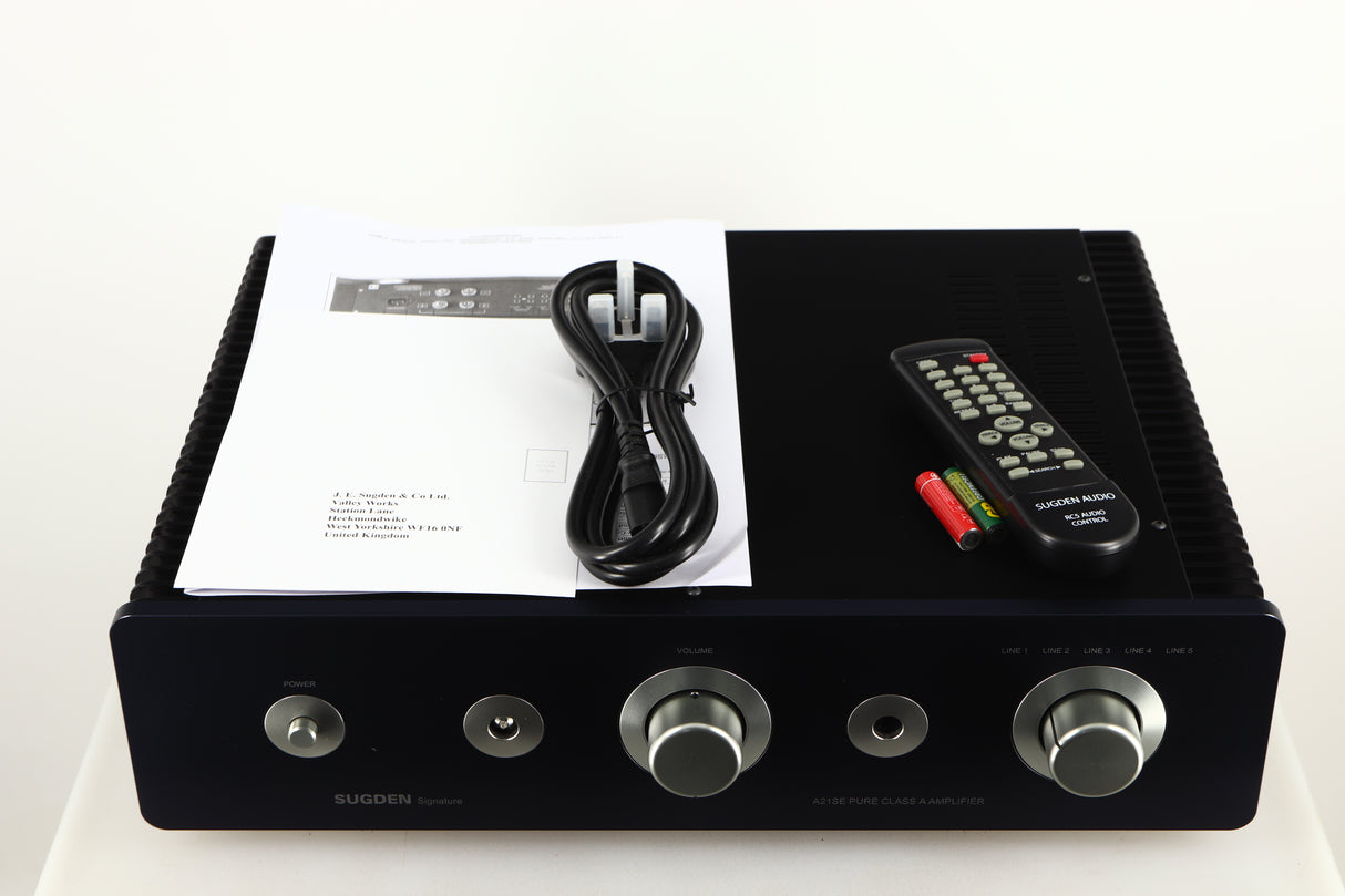 Top of a used Sugden A21SE Signature Integrated Amplifier in a graphite finish showing Mains Cable, Manual, Remote and Batteries