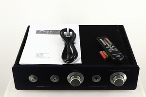 Top of a used Sugden A21SE Signature Integrated Amplifier in a graphite finish showing Mains Cable, Manual, Remote and Batteries