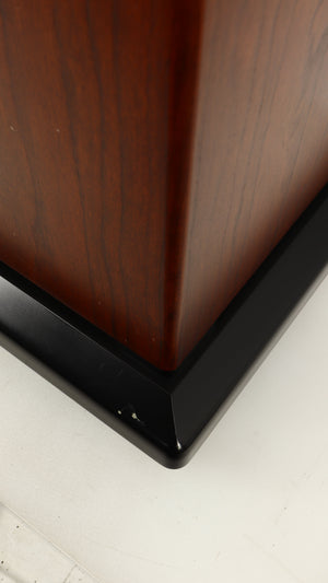 Close up of a used Sugden LS-21 Floorstanding Speaker in a dark cherry finish showing scratch on base