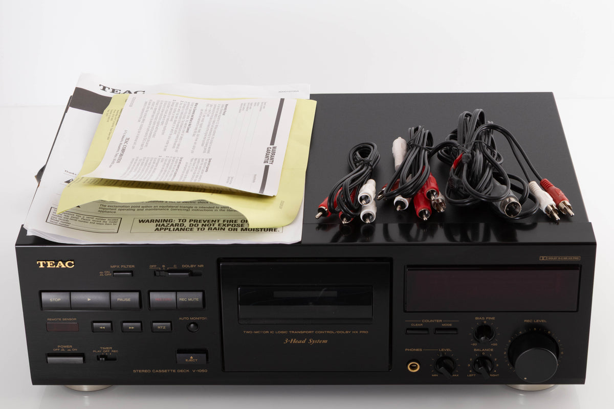 Top of a used TEAC V-1050 Cassette Deck in a Black finish showing Manual and Interconnect Cables