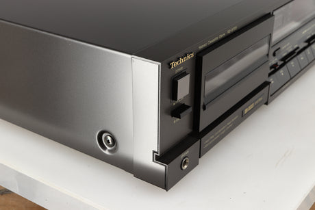 Front left corner of a used Technics RS-B705 Cassette Deck in a black finish