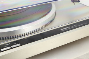 Close up view of a used Technics SL-Q2 Direct Driver Turntable in Silver showing some scratching on the turntable and the lid