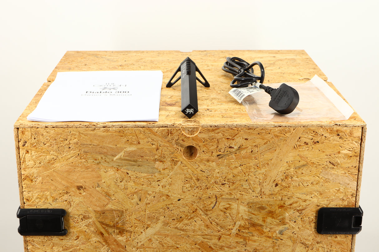 Box of a used The Gryphon Diablo 300 Integrated Amplifier showing mains cable, manual, and remote