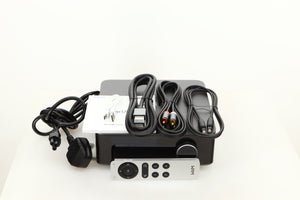 Top of a used Wiim Amp Ultra Streaming Amplifier in a grey finish showing Remote, Manual, Power Cable, USB Cable, Interconnect Cable, HDMI Cable and Optical Cable