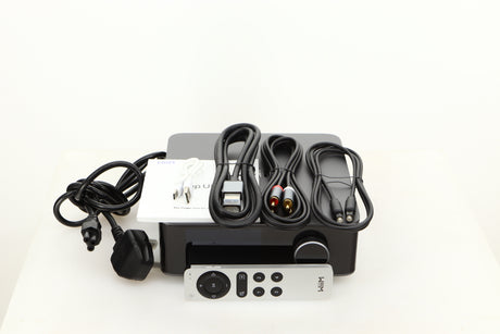Top of a used Wiim Amp Ultra Streaming Amplifier in a grey finish showing Remote, Manual, Power Cable, USB Cable, Interconnect Cable, HDMI Cable and Optical Cable