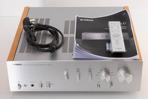 Top of a used Yamaha A-S2000 Integrated Amplifier in a Silver finish showing Mains Cable, Remote, Batteries and Manual