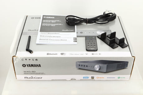 Box of a used Yamaha WXC-50 Streaming Pre Amplifier in Silver finish with mains cable, manual, remote, antenna, and stands 